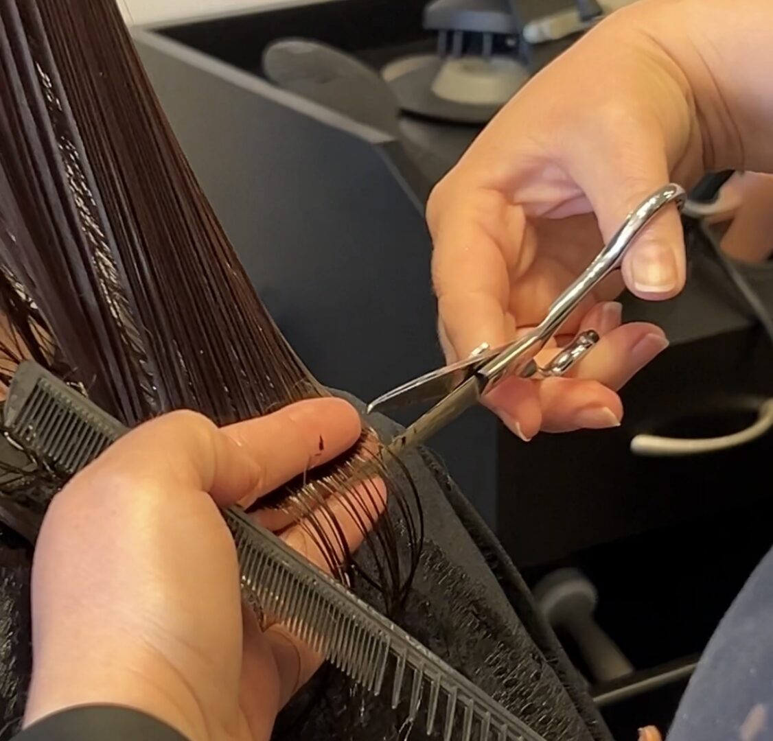 Stylist trimming wet hair with scissors